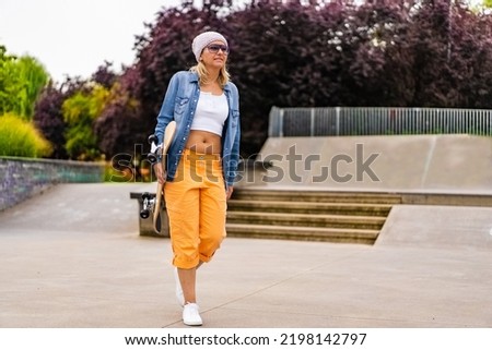 Young woman sitting with skateboard in skate park 
