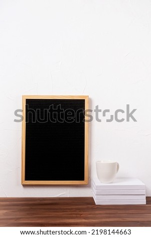 felt letter board mockup hanging on the wall with stack of books and coffee cup , mockup design