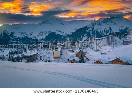 Famous alpine winter ski resort with buildings and stunning mountains at dawn. Great resort and ski slopes at sunrise, La Toussuire, Rhone Alps, France, Europe Royalty-Free Stock Photo #2198148463