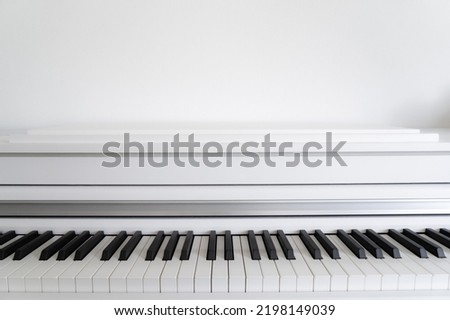 White piano keyboard horisontally, white wall