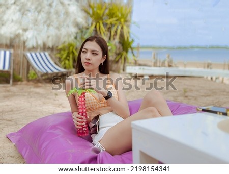 woman wearing short pants and top bra sitting on the beanbag seeing the sky on the beach