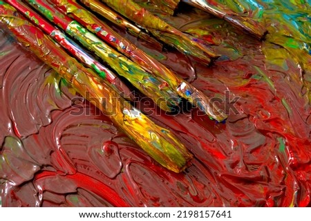 Close up on grungy paint brushes on messy artist canvas covered with oil paints conceptual representation for fine art gallery, visual artistic genius and talented painter's workshop Royalty-Free Stock Photo #2198157641