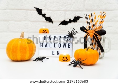 halloween light background with place for text .Pumpkin candles jolly roger and board with inscription happy halloween on white brick wall background with bats and spiders. Decorating a Halloween 