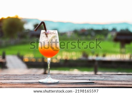 Orange soda is placed on a bar in the middle of the field in the evening. It is a refreshing drink with a refreshing atmosphere and a beautiful background.