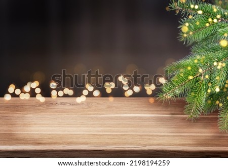 Winter or christmas tree background. Empty wood table and branch of fir tree with defocused lights. Template for product display. Royalty-Free Stock Photo #2198194259