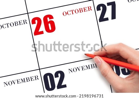 26th day of October. A hand holding a red pen and pointing on the calendar date October 26. Red calendar date, copy space, mockup. Autumn month, day of the year concept.