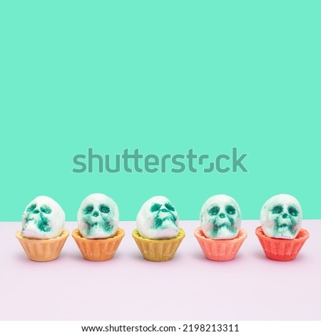 Five skulls in tart shells on turquoise and white. Halloween background.