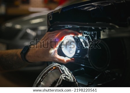 Car headlight in repair close-up. The car mechanic installs the lens in the headlight housing. The concept of a car service.Installation of LED lenses in the headlight. LED lens.Restoration of optics. Royalty-Free Stock Photo #2198220561
