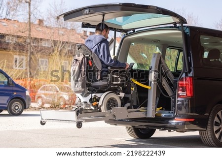 Man with disability using hydraulic wheelchair lift to get in the van, after a summer day spent on beautiful mountain nature Royalty-Free Stock Photo #2198222439