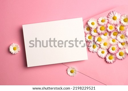 Invitation card mockup with envelope and white daisy flowers on pink, flat lay with blank card