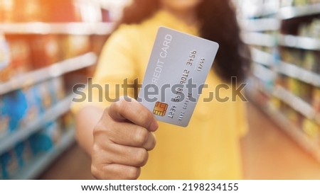 Woman at the supermarket she is paying credit card shopping concept. Credit card shopping in supermarket hand holding credit card payment. hand holding credit card blur supermarket store background.