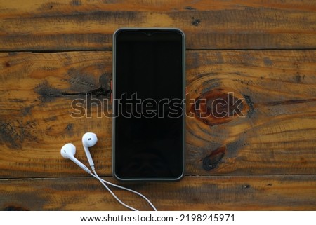 Smartphone and headpset on wooden background. vintage background 