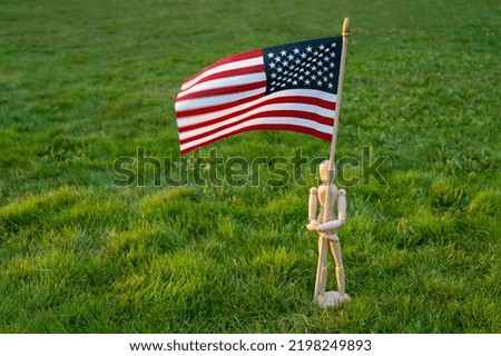 Independence day USA. Veterans day USA. Memorial day concept. Wooden mannequin with American flag on green grass background