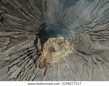 Seeing the inside of a volcano crater with smoke in east Java, Indonesia. Aerial view of volcano crater Mount Gunung Bromo, Tengger Semeru National Park.