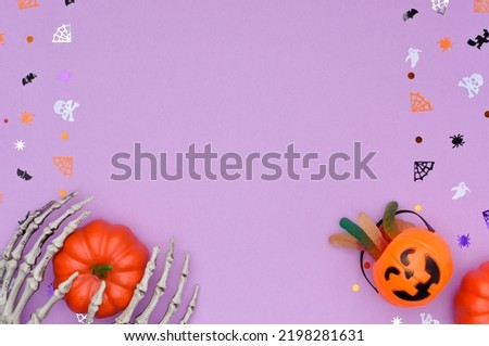 Happy Halloween concept. Halloween background with skeleton hands hold a pumpkin and candy bucket. Decorated with pinata confetti in the shape of skulls, spiders, spider webs, bats and ghosts.