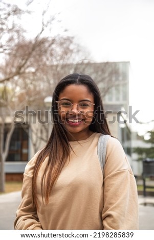 Vertical portrait of happy and smiling black teen girl outdoors looking at camera. Copy space.