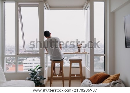 Lonely asian man sit by windows in the room. Concept lonely single broken heart. Royalty-Free Stock Photo #2198286937