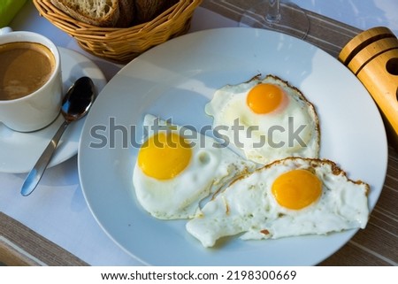 Image of plate with fried eggs at plate and cup of coffee, breakfast in cafe