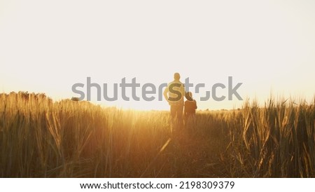 Farmer and his son in front of a sunset agricultural landscape. Man and a boy in a countryside field. Fatherhood, country life, farming and country lifestyle. Royalty-Free Stock Photo #2198309379
