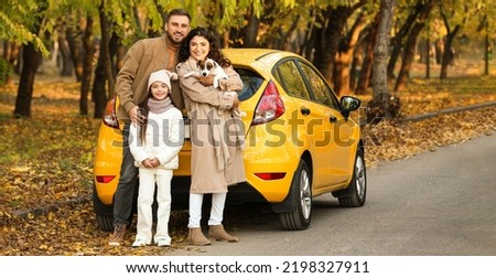 Happy family with cute dog near yellow car on autumn day Royalty-Free Stock Photo #2198327911