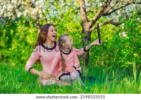 mother and daughter take pictures using a tablet in nature