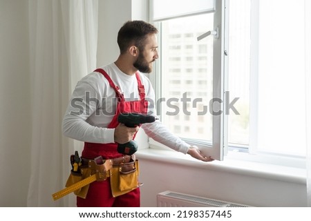 handsome young man installing bay window in a new house construction site.
