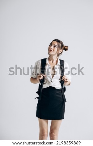 High school student in a white shirt and skirt holding a black backpack