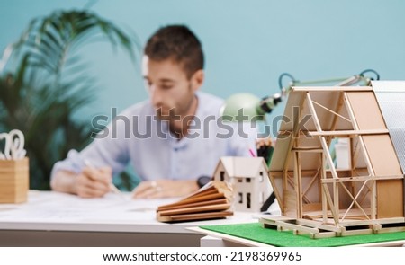 A young architect engaged in the design of an innovative modular, zero-impact housing structure. Concept of New Solutions for Sustainable Architecture.  Royalty-Free Stock Photo #2198369965