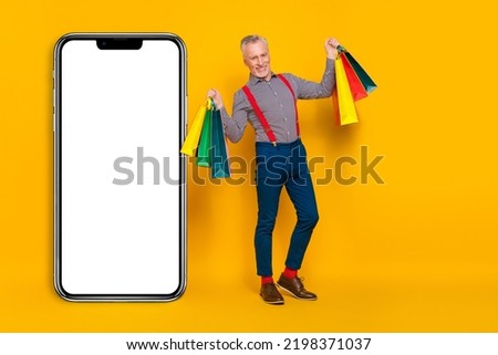 Full length body size view of attractive cheery man holding bags copy space isolated over bright yellow color background