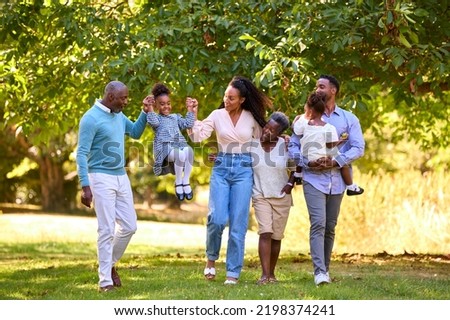 Multi-Generation Family Enjoying Walk In Countryside Together Swinging Granddaughter Royalty-Free Stock Photo #2198374241