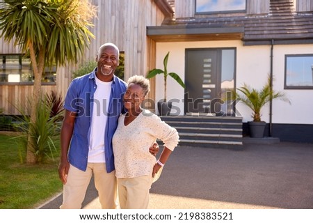 Portrait Of Senior Couple Standing In Driveway In Front Of Dream Home Together