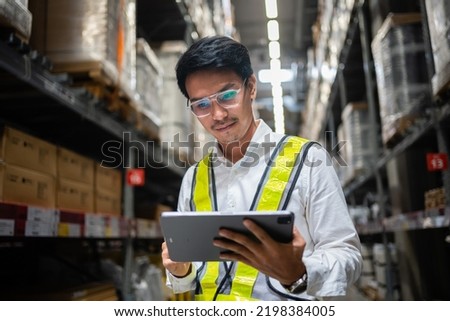 A male worker working in a warehouse uses a digital tablet to inspect the goods on the shelves to manage the products in the warehouse. Logistics business planning concept. Industrial concept. 