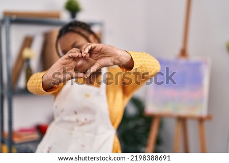 African american woman with braids at art studio smiling in love showing heart symbol and shape with hands. romantic concept. 