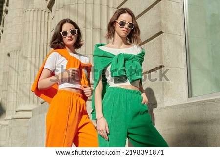 Sport fashion, sport casual style. Beautiful female models poses in bright sports suits and sunglasses on the city street. Fashion shot. Royalty-Free Stock Photo #2198391871