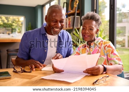 Smiling Senior Couple Sitting Around Table At Home Reviewing Finances Royalty-Free Stock Photo #2198394045
