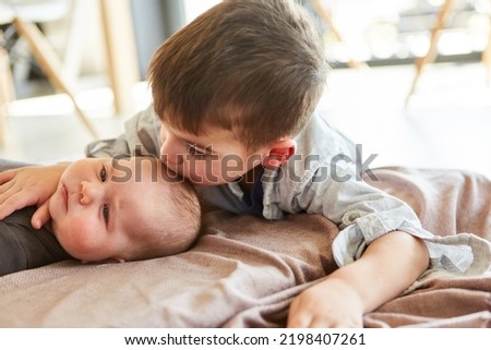 Little boy as big brother gives baby a kiss on the forehead for love and affection Royalty-Free Stock Photo #2198407261