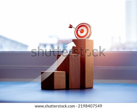 Shining rise up arrow shoot up towards the goal, 3d target icon on the top of wooden cube blocks, bar graph chart steps, business growth process, technology trend, economic improvement concepts. Royalty-Free Stock Photo #2198407549