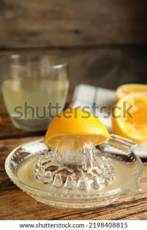 Squeezer with lemon and juice on wooden table
