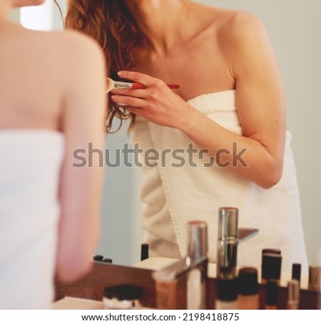 Young woman looking in the mirror and putting make-up on.
