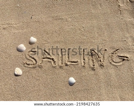 on the beach is carved with letters in the smooth sand the writing Sailing