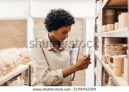 Ceramic store owner taking a picture of her handmade earthenware products. Young female ceramist photographing content for her online store. Creative female entrepreneur running a small business.