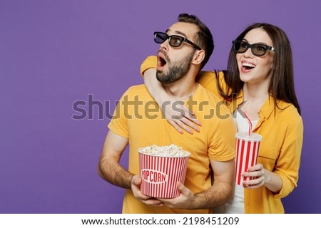 Young couple two friends woman man in 3d glasses watch movie film hold bucket of popcorn cup of soda pop look aside isolated on plain violet background. People emotions in cinema lifestyle concept. Royalty-Free Stock Photo #2198451209