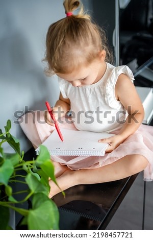 Little girl draw or write by red pencil at home. Child creativity and education concept. High quality photo