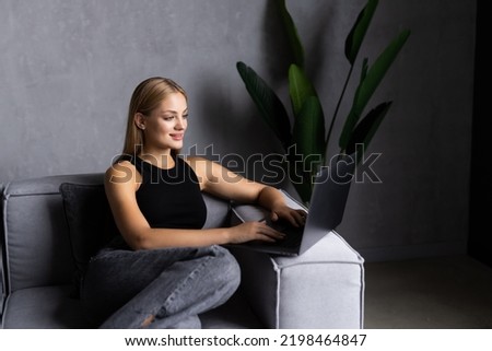 Young woman using a mobile phone and laptop while working from home