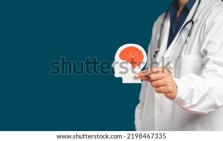 Midsection of doctor in uniform holding a white head with a red brain symbol made from paper while standing on a blue background. Space for text. Medical and healthcare concept Royalty-Free Stock Photo #2198467335