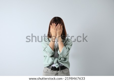 Young girl hiding face in hands on white background Royalty-Free Stock Photo #2198467633