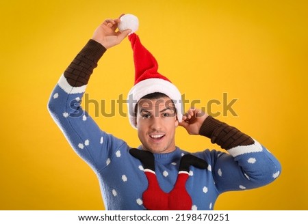 Surprised man wearing Santa hat on yellow background