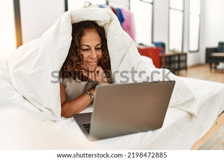Middle age hispanic woman smiling confident using laptop at bedroom
