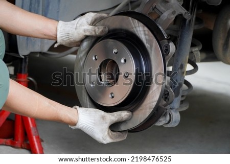 Asian mechanic replaces new brake discs in garage cars. Royalty-Free Stock Photo #2198476525