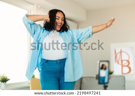 Cheerful African American Female Blogger Making Video On Mobile Phone Dancing And Having Fun Posing At Home, Wearing Plus Size Clothes. Professional Lifestyle Blogging And Social Media